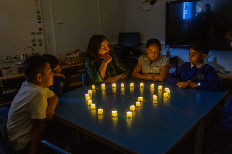 a picture of a teacher and students sat around candles